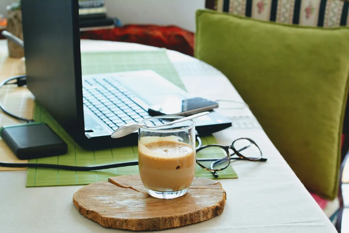 home office desk with coffee and laptop Glass of coffee in front of a laptop and glasses on a desk
